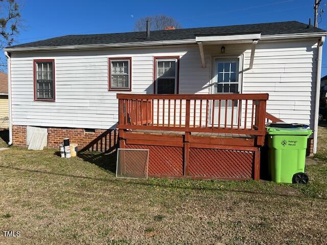 back of property featuring a lawn and a deck