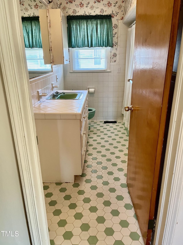 bathroom with vanity and tile walls