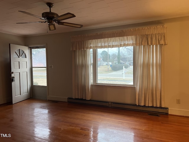 empty room with crown molding, hardwood / wood-style flooring, a baseboard radiator, and ceiling fan