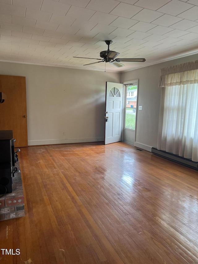 405 N Wilson Ave, Dunn, NC 28334 - unfurnished living room featuring a ceiling fan, crown molding, wood finished floors, a baseboard heating unit, and baseboards