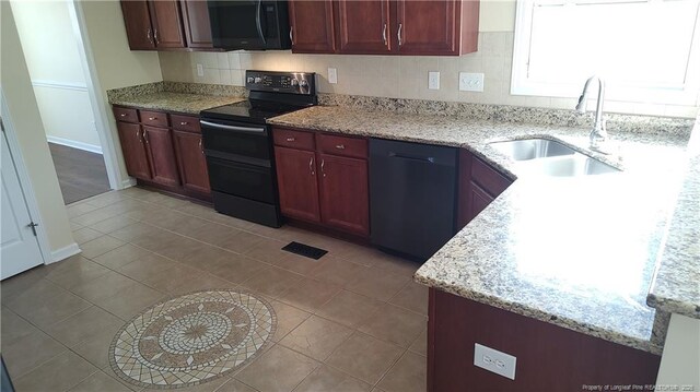 3922 Tasha Dr, Hope Mills, NC 28348 - kitchen featuring sink, decorative backsplash, light tile patterned floors, black appliances, and light stone countertops