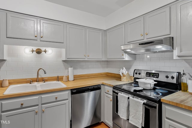 kitchen with tasteful backsplash, appliances with stainless steel finishes, sink, and butcher block countertops