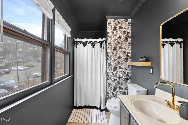 bathroom with ornamental molding, plenty of natural light, and toilet