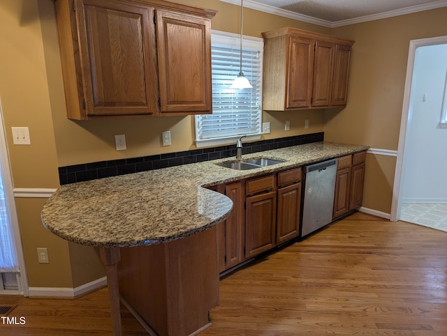 kitchen featuring dishwasher, sink, a kitchen bar, ornamental molding, and light wood-type flooring