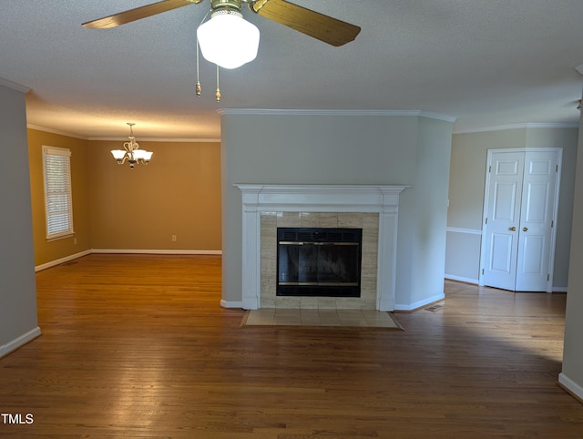 unfurnished living room featuring dark wood-type flooring, a fireplace, ornamental molding, a textured ceiling, and ceiling fan with notable chandelier