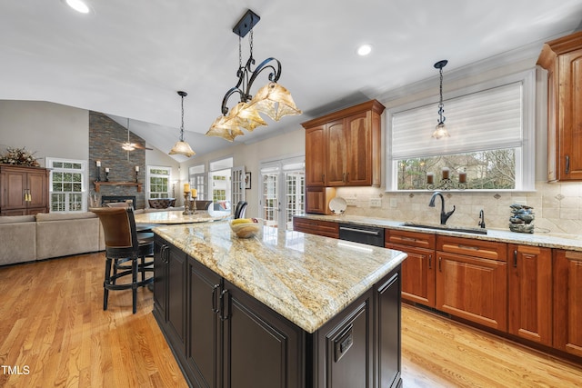 kitchen featuring french doors, sink, light wood-type flooring, a kitchen island, and light stone countertops