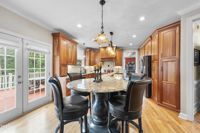 kitchen with stainless steel fridge, light stone countertops, hanging light fixtures, and a kitchen island