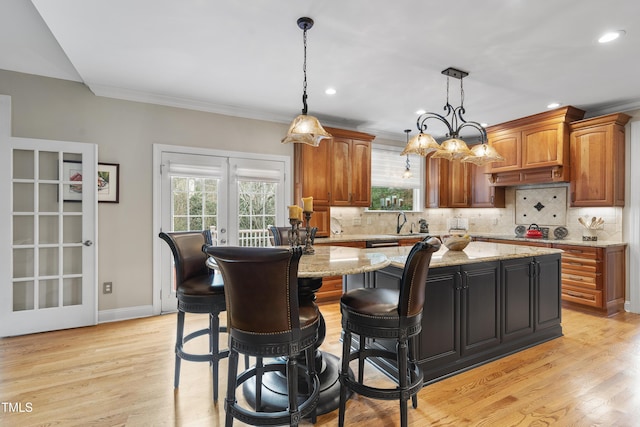 kitchen featuring french doors, tasteful backsplash, light stone counters, and a kitchen island