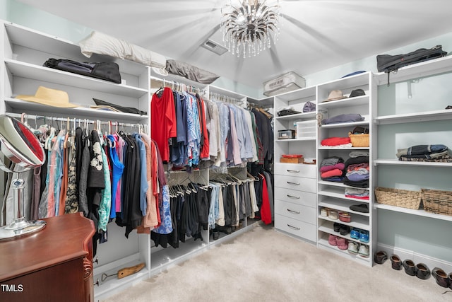 walk in closet with light colored carpet and a chandelier