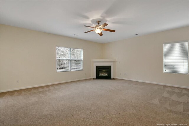 323 River Oak St, Spring Lake, NC 28390 - unfurnished living room with light colored carpet, baseboards, ceiling fan, and a fireplace with flush hearth