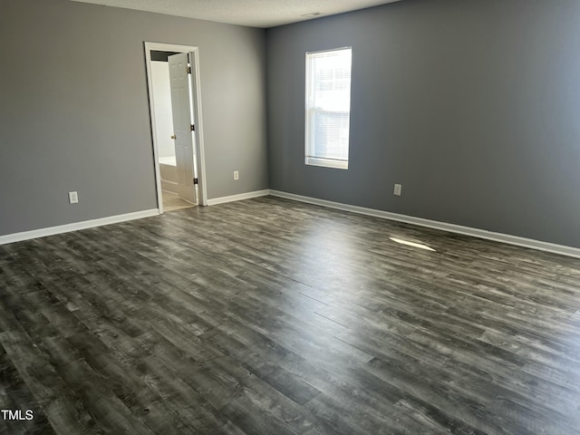 empty room with dark hardwood / wood-style flooring and a textured ceiling