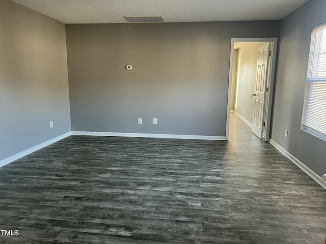 empty room featuring dark hardwood / wood-style flooring and a textured ceiling