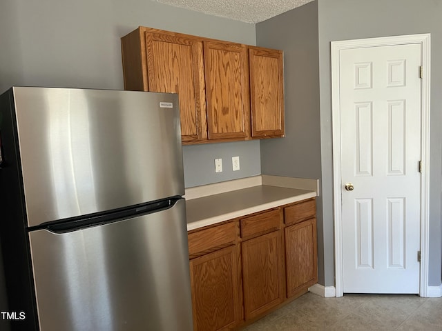 kitchen with stainless steel fridge, a textured ceiling, and light tile patterned flooring