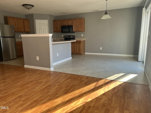 kitchen with a center island, a textured ceiling, light wood-type flooring, appliances with stainless steel finishes, and pendant lighting