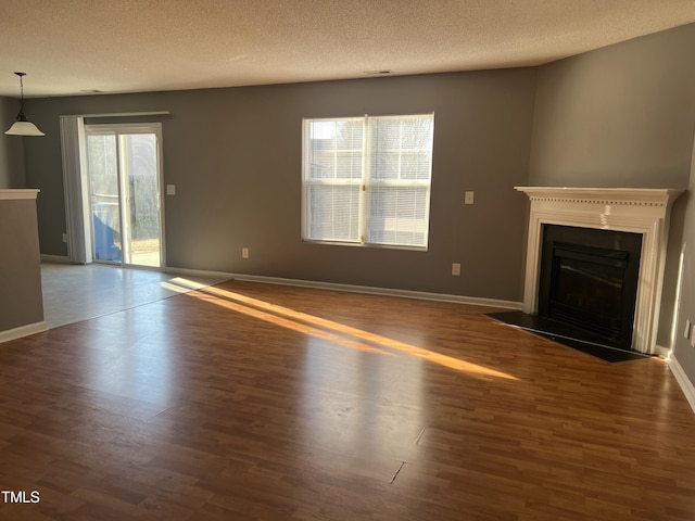 unfurnished living room with dark wood-type flooring, a wealth of natural light, and a textured ceiling