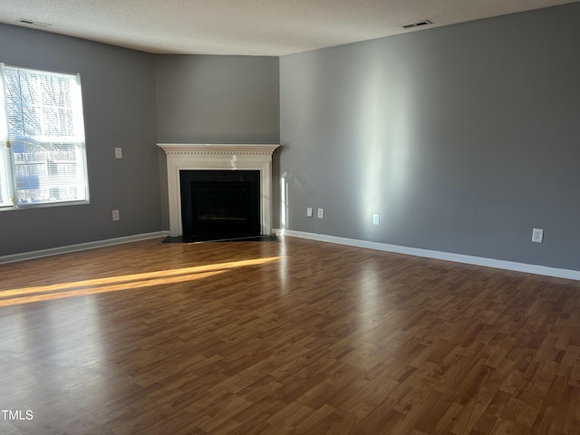 unfurnished living room with dark hardwood / wood-style floors and a textured ceiling