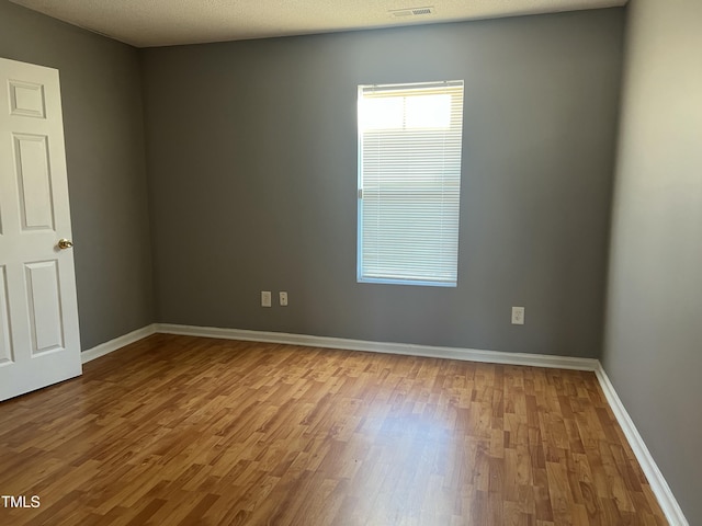 empty room with light hardwood / wood-style flooring and a textured ceiling