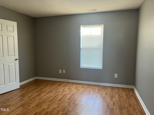 unfurnished room featuring light hardwood / wood-style flooring and a textured ceiling