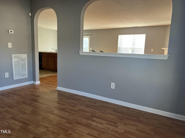 spare room with sink, a healthy amount of sunlight, hardwood / wood-style floors, and a textured ceiling