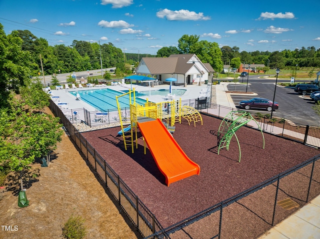 view of playground featuring a community pool and a patio