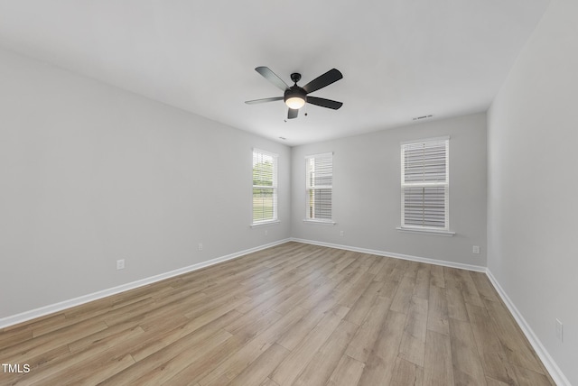 spare room with ceiling fan, light wood-type flooring, visible vents, and baseboards