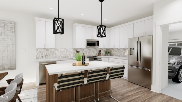 kitchen with stainless steel appliances, a center island, white cabinets, and decorative light fixtures