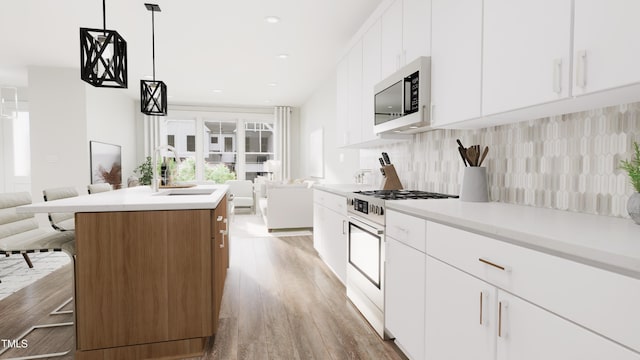 kitchen featuring high end stainless steel range oven, white cabinetry, a kitchen island with sink, and pendant lighting