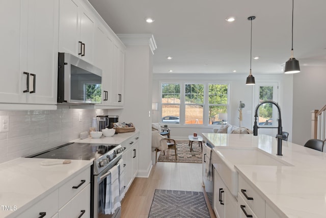 kitchen with light stone counters, decorative light fixtures, stainless steel appliances, and white cabinets