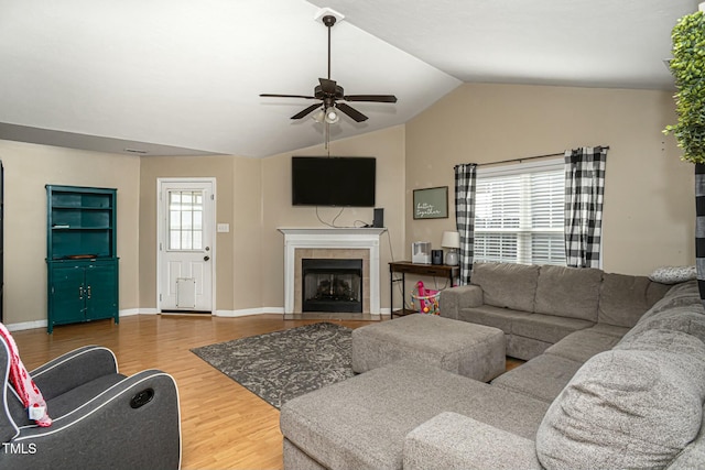 living room with hardwood / wood-style floors, vaulted ceiling, a tile fireplace, and ceiling fan