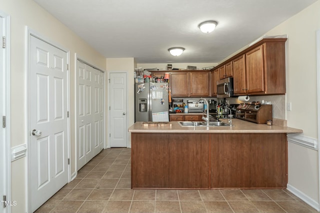 kitchen with sink, stainless steel appliances, kitchen peninsula, and light tile patterned flooring