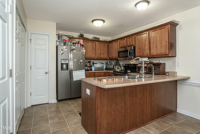 kitchen with tile patterned flooring, sink, kitchen peninsula, and appliances with stainless steel finishes