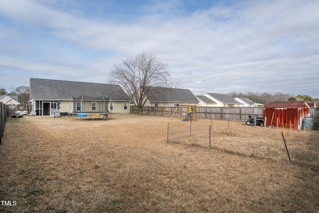 view of yard featuring a storage shed, a playground, and a trampoline