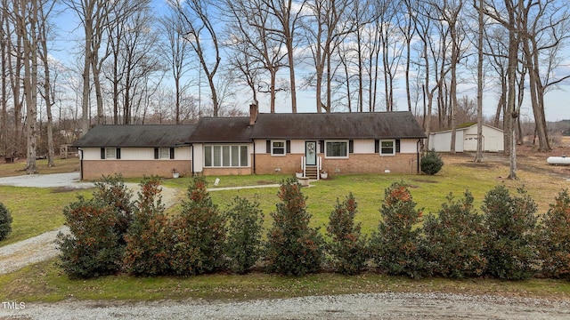 ranch-style house with a garage, an outbuilding, and a front lawn