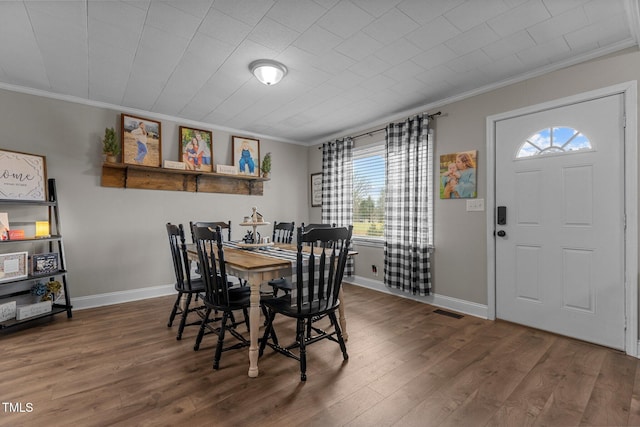 dining area featuring ornamental molding and dark wood-type flooring