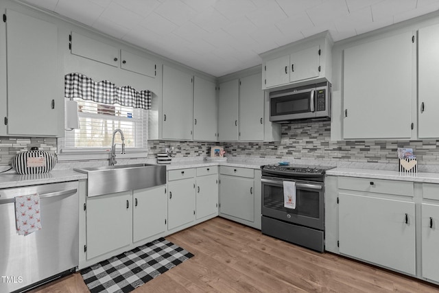 kitchen featuring stainless steel appliances, light hardwood / wood-style floors, sink, and decorative backsplash