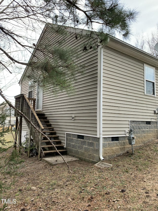 view of side of property featuring crawl space and stairs