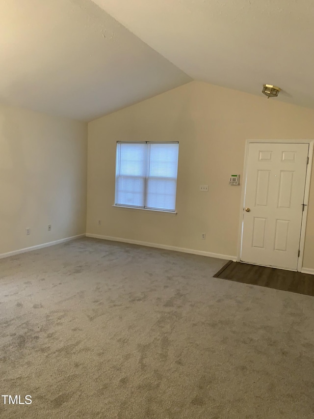 interior space with vaulted ceiling, dark carpet, and baseboards