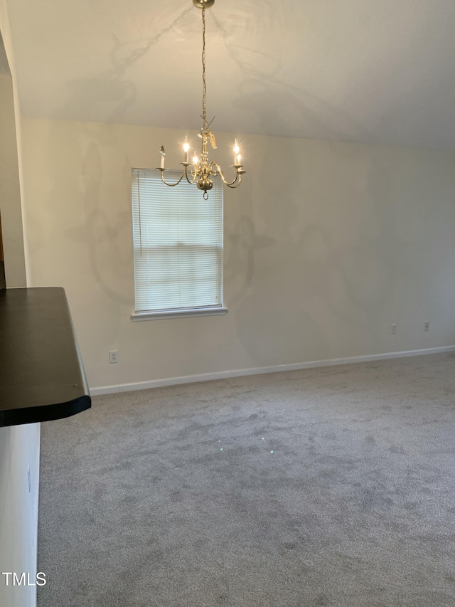 unfurnished dining area with a chandelier, carpet flooring, and baseboards