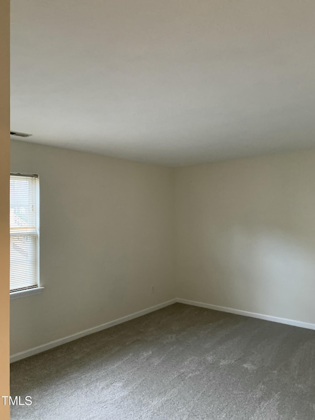 unfurnished room featuring carpet flooring, visible vents, and baseboards