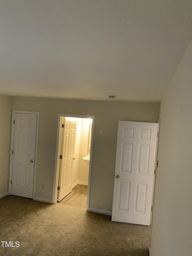 unfurnished bedroom featuring carpet flooring, baseboards, and ensuite bathroom