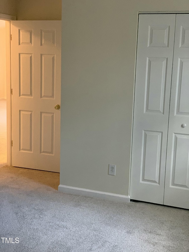 unfurnished bedroom with carpet floors, baseboards, and a closet