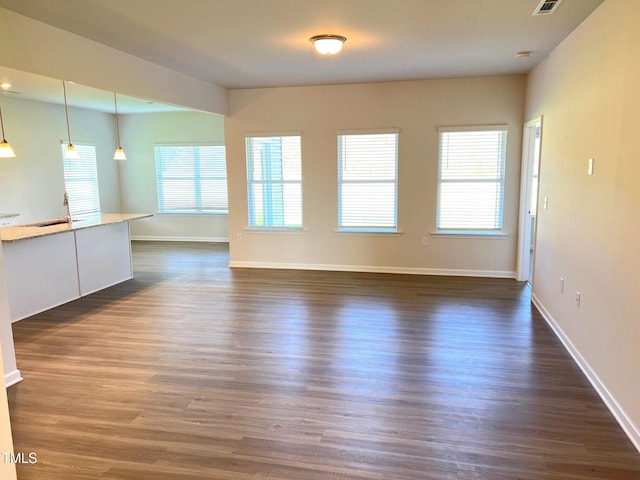 unfurnished living room with plenty of natural light, sink, and dark hardwood / wood-style floors