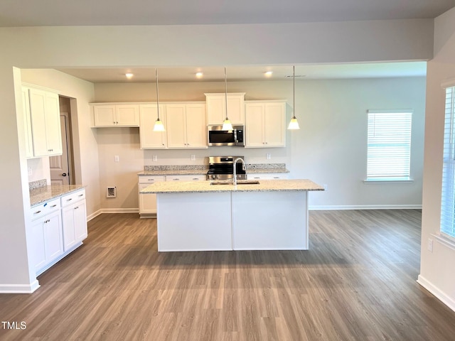 kitchen with appliances with stainless steel finishes, pendant lighting, white cabinets, and light stone counters