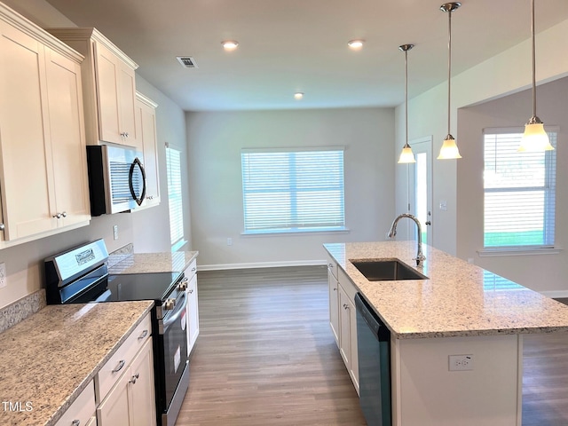 kitchen featuring sink, light stone counters, a center island with sink, stainless steel appliances, and white cabinets