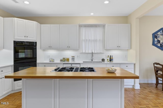 kitchen featuring sink, white cabinets, a kitchen island, wood counters, and stainless steel gas stovetop