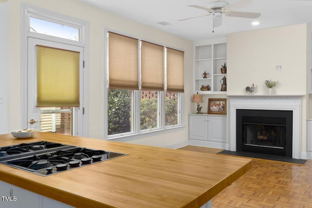 kitchen with gas stovetop, built in shelves, light parquet flooring, and ceiling fan