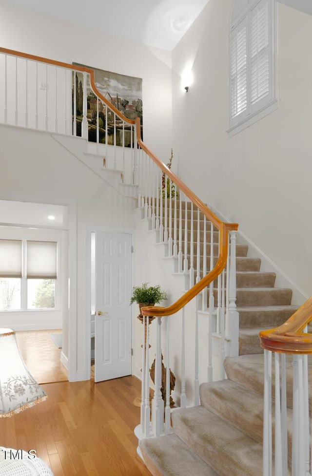 stairs with hardwood / wood-style flooring and a towering ceiling