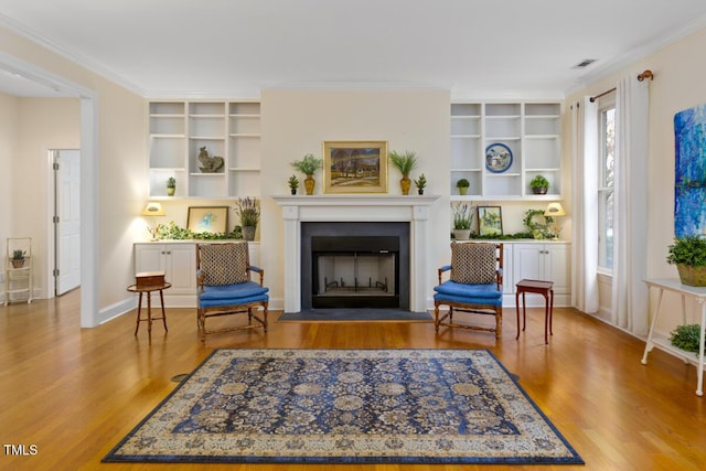 living area with hardwood / wood-style flooring, crown molding, and built in features