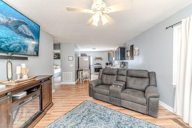 living room with ceiling fan, wood-type flooring, and a textured ceiling