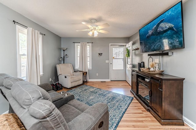 living room featuring plenty of natural light, a textured ceiling, ceiling fan, and light hardwood / wood-style flooring